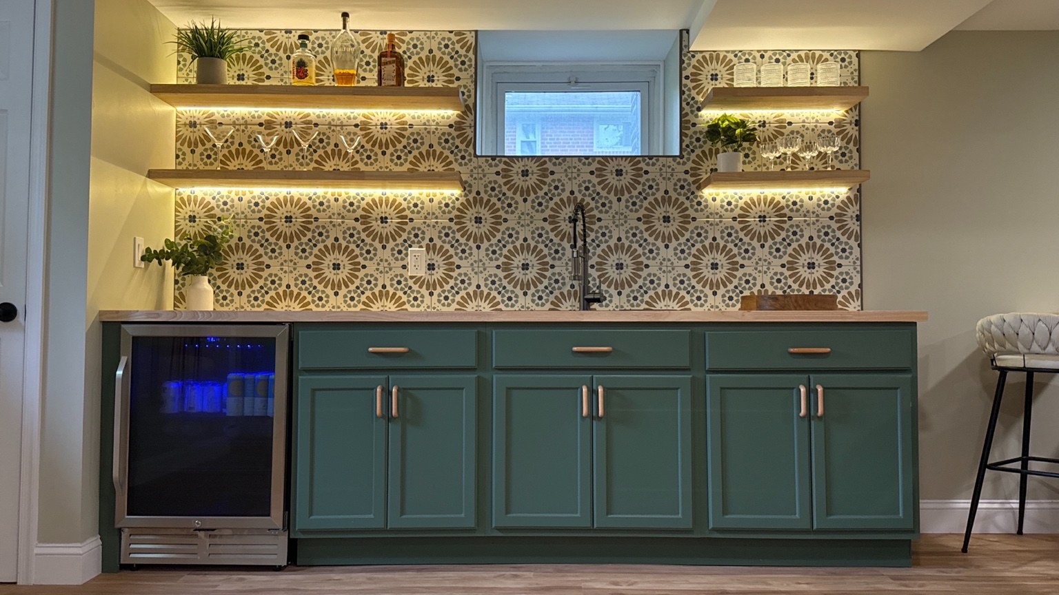 Finished custom basement wet bar with tile backsplash and illuminated shelving