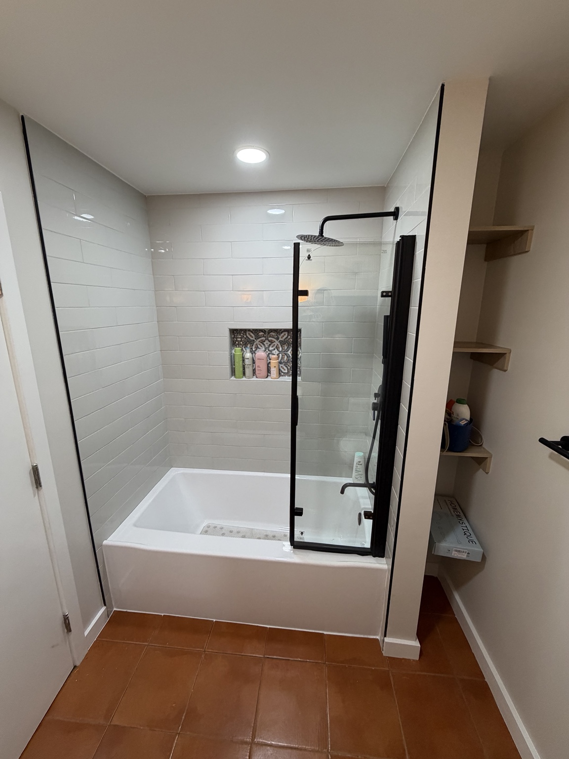 Finished tub shower renovation with tiled surround and glass panel